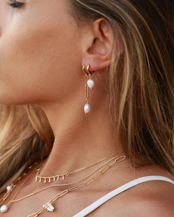 Boucles d'oreilles Nilaï S Perla avec perle d'eau douce baroque montée sur une chaîne dorée, vendues chez Fata Morgana Creation